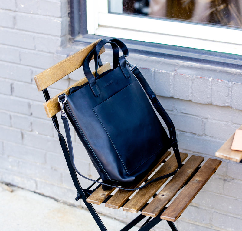 Made Free Luxury Black Leather tote bag rests on a chair.